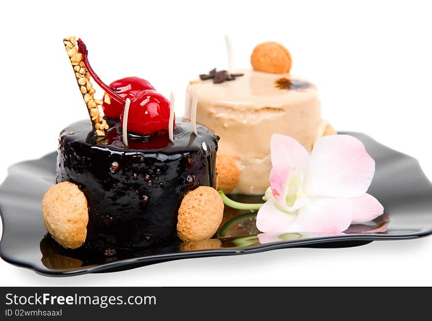 Cake with white and dark chocolate on the black plate isolated on a white background.