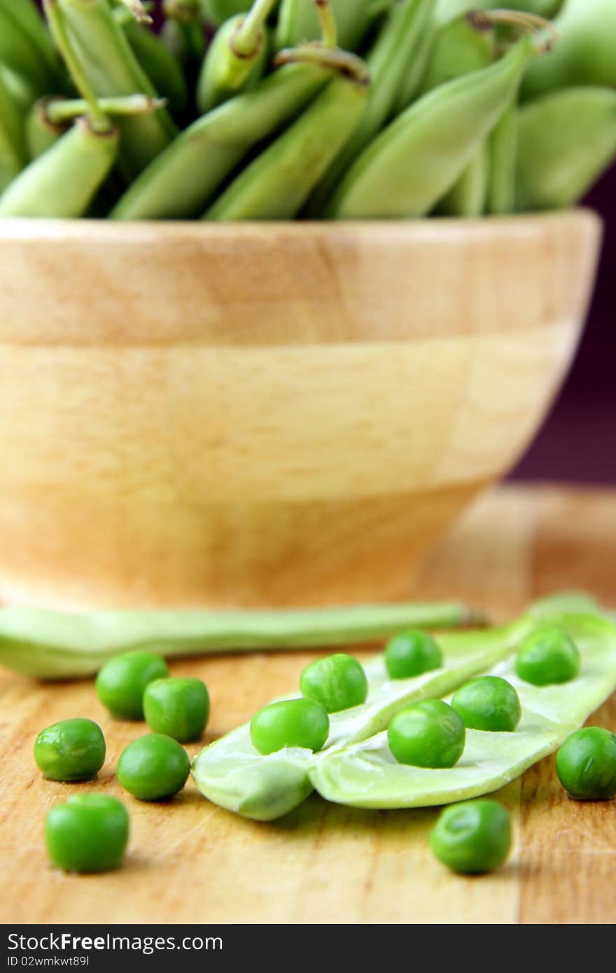 green peas in a wooden bowl and on the board