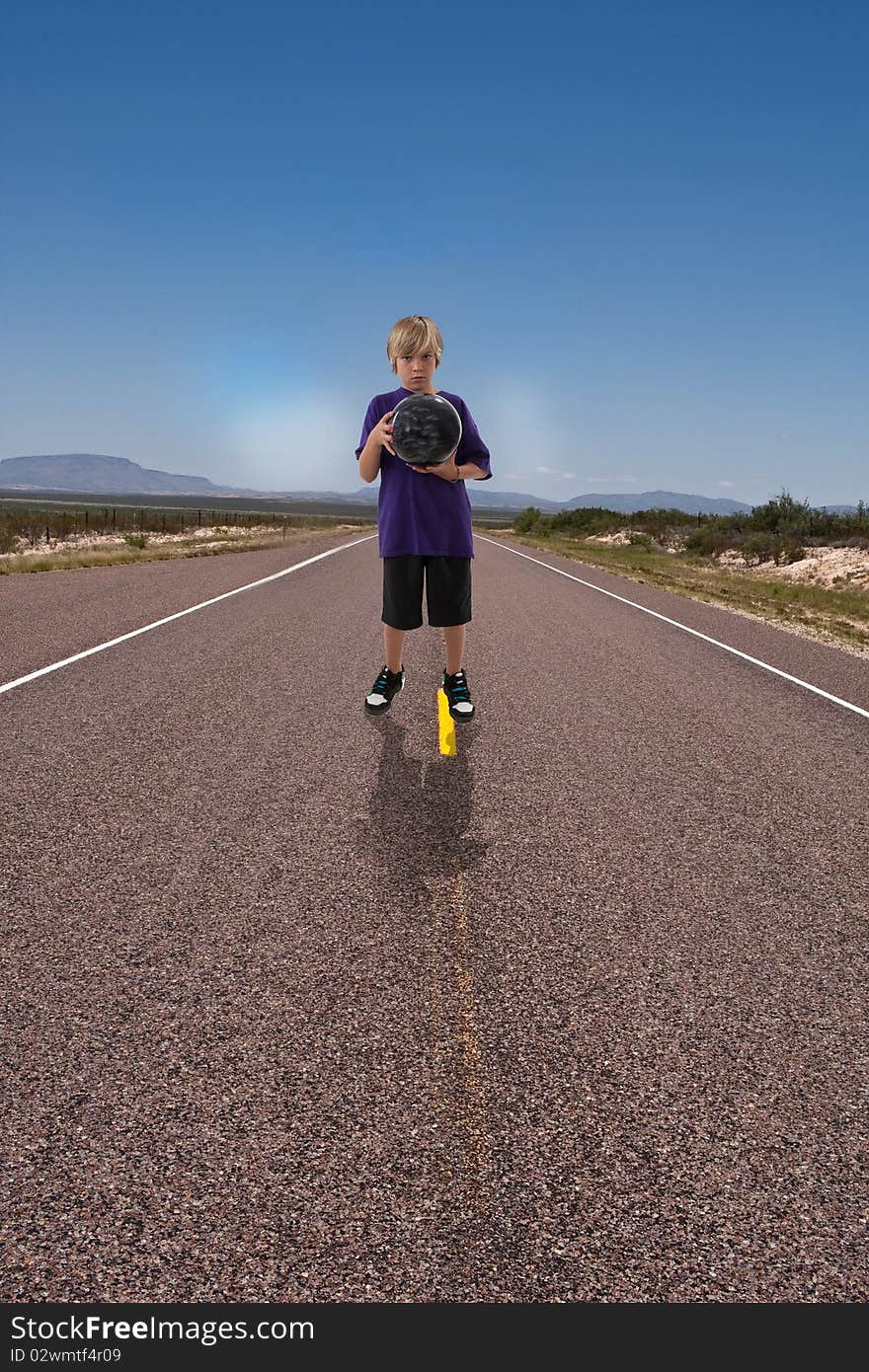 Boy holding bowling ball ready to bowl down deserted highway. Boy holding bowling ball ready to bowl down deserted highway.