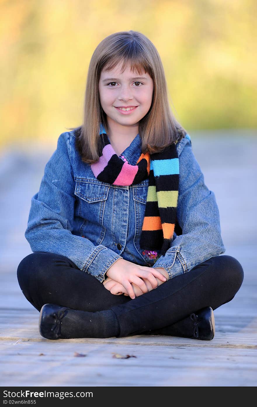 Young brunette caucasian girl sitting with legs crossed on wooden boardwalk. Young brunette caucasian girl sitting with legs crossed on wooden boardwalk