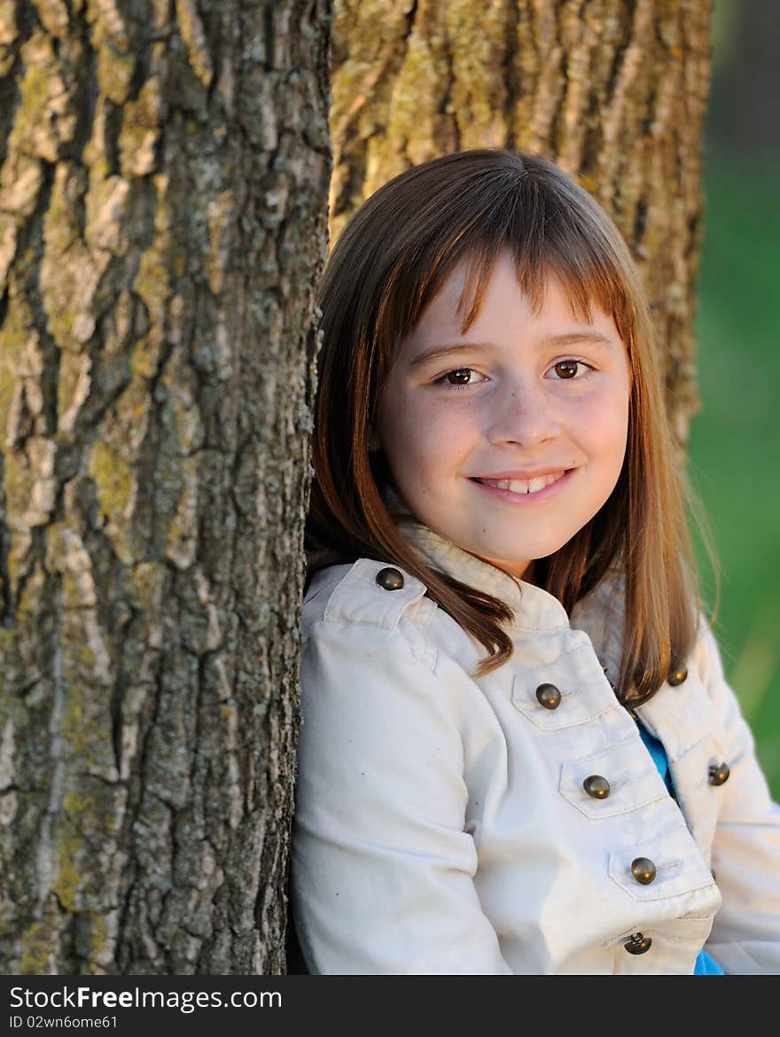 Young caucasian, brunette girl leaning against bark of tree. Young caucasian, brunette girl leaning against bark of tree