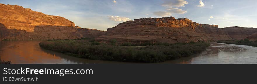 Orange sandstone cliffs reflected in a river at sunset. Orange sandstone cliffs reflected in a river at sunset