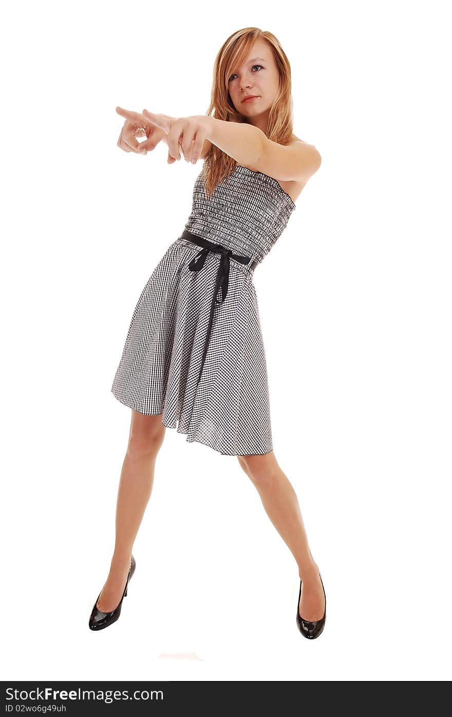 A young pretty blond woman in a black white dress and black heels, standing in the studio, pointing with her fingers, over white background. A young pretty blond woman in a black white dress and black heels, standing in the studio, pointing with her fingers, over white background.