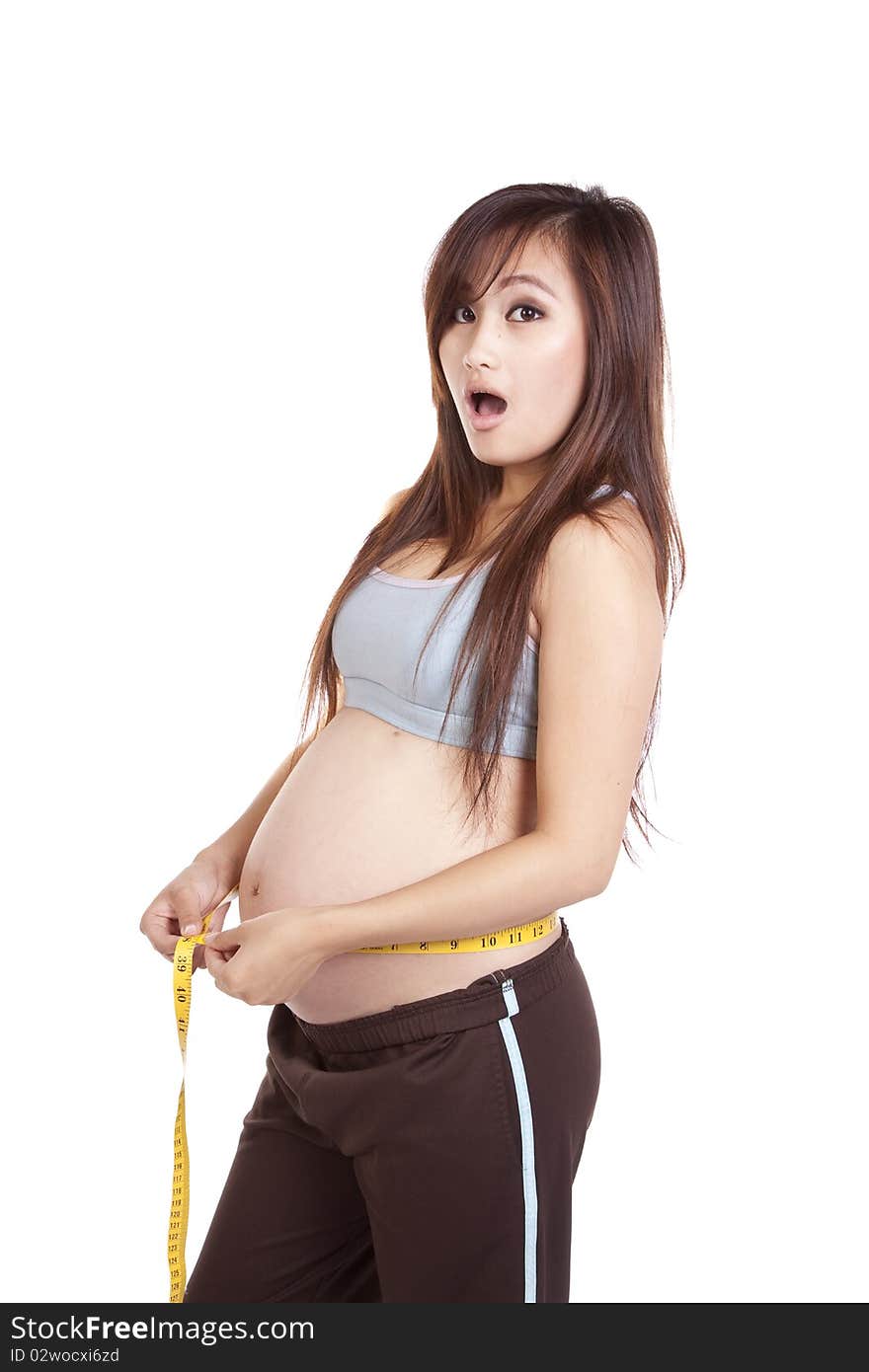 A woman showing her belly and measuring her pregnant stomach. A woman showing her belly and measuring her pregnant stomach.