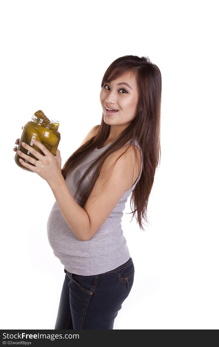 A pregnant woman is snacking on a pickle. A pregnant woman is snacking on a pickle.