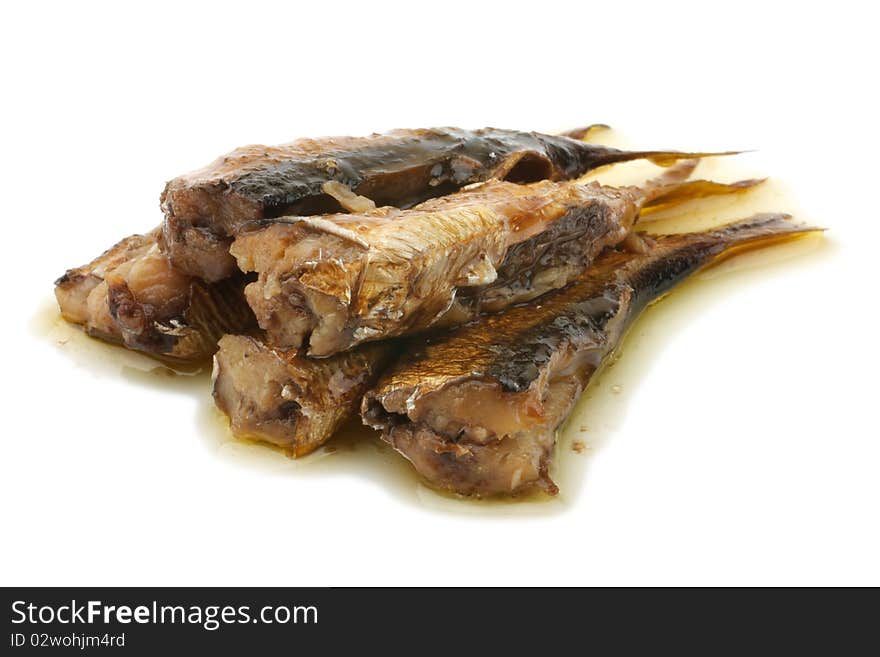 Shows a handful of sprats. Smoked sprats in oil. Oil flows from sprat. Isolated on white background.