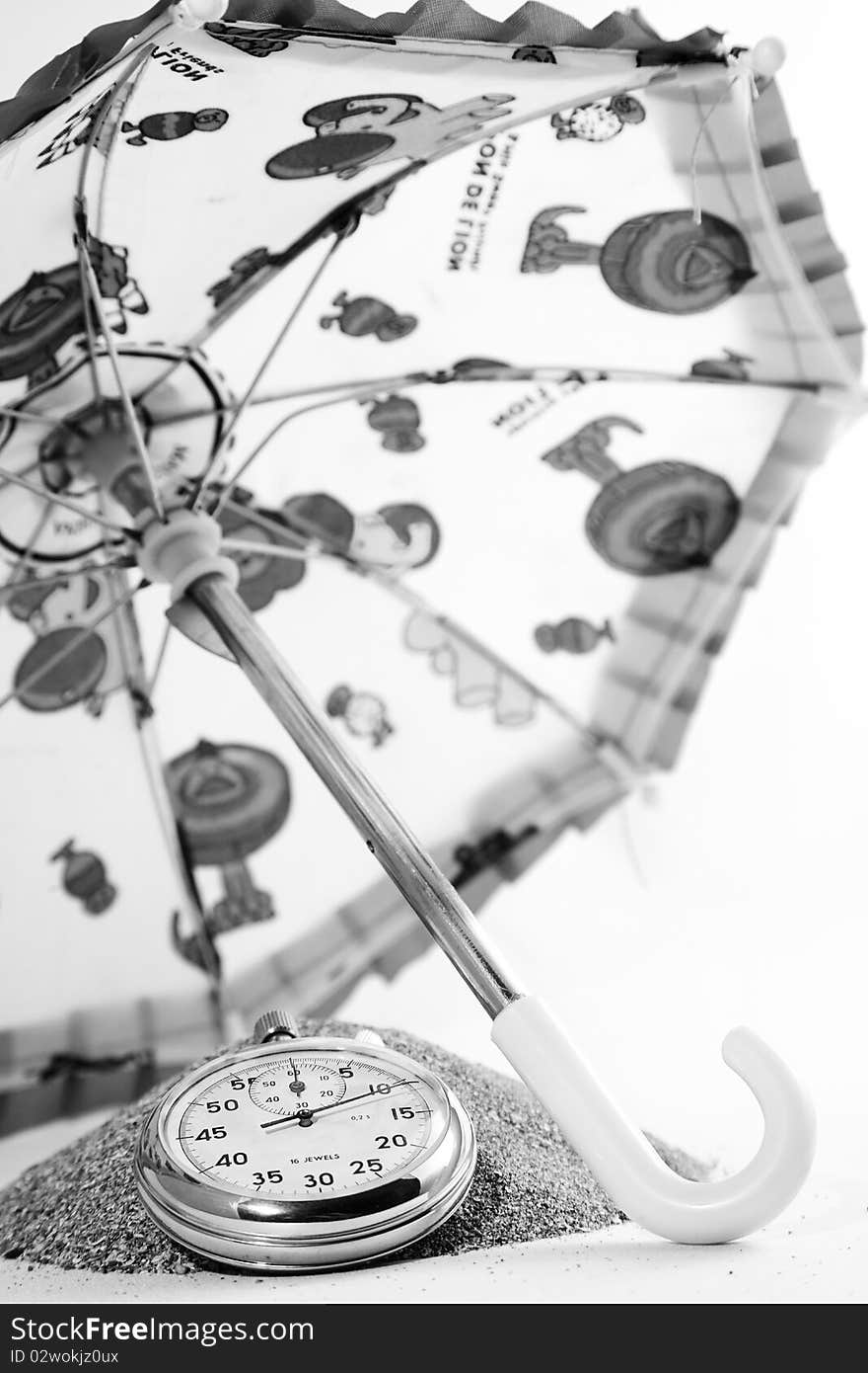 Old clock on sand handful with umbrella. Old clock on sand handful with umbrella