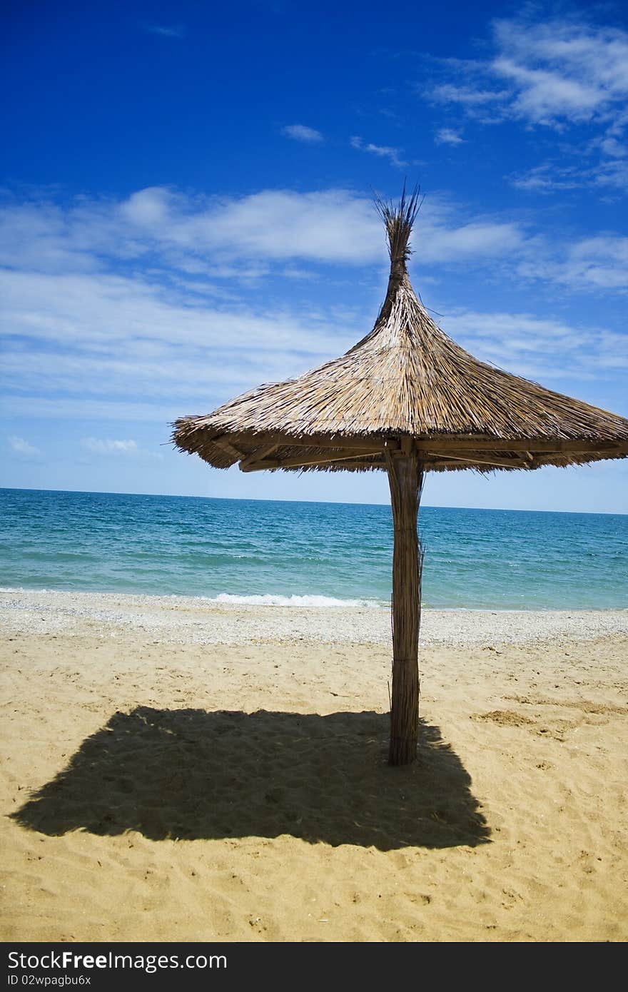 A beach umbrella covered in thatch, on a beach in Romania