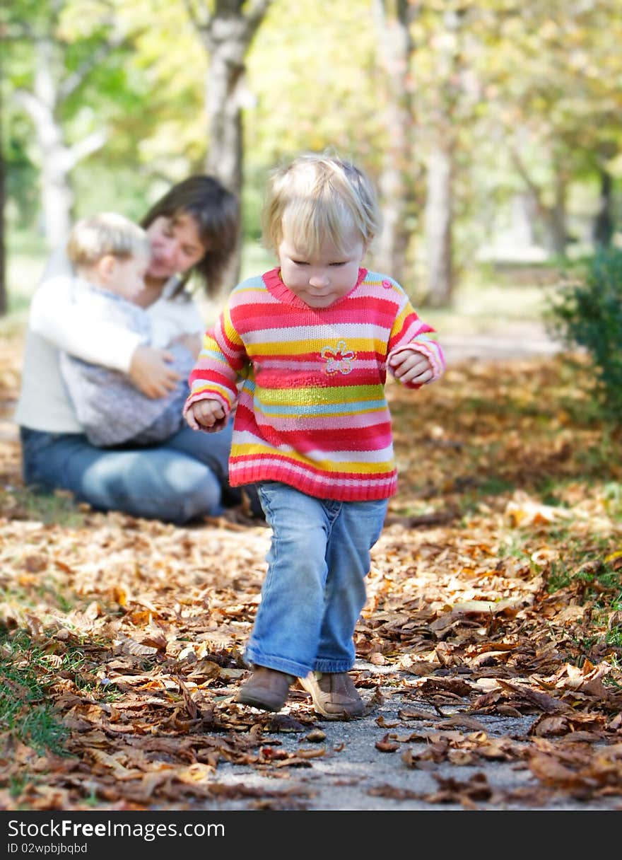 Young girl on mother and brother background in autumn park