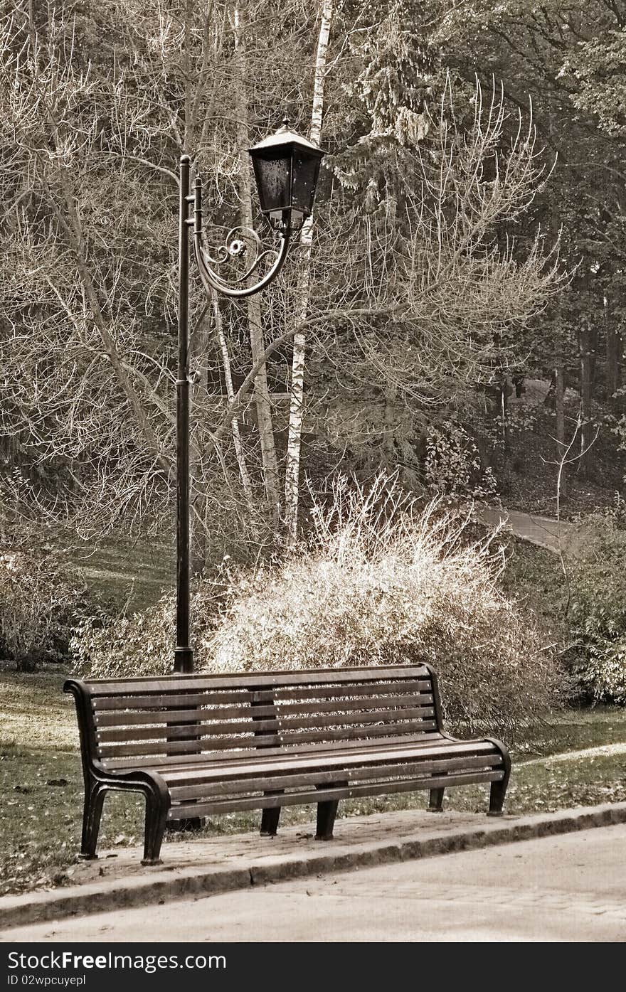 Old sepia photo of the bench in autumn park