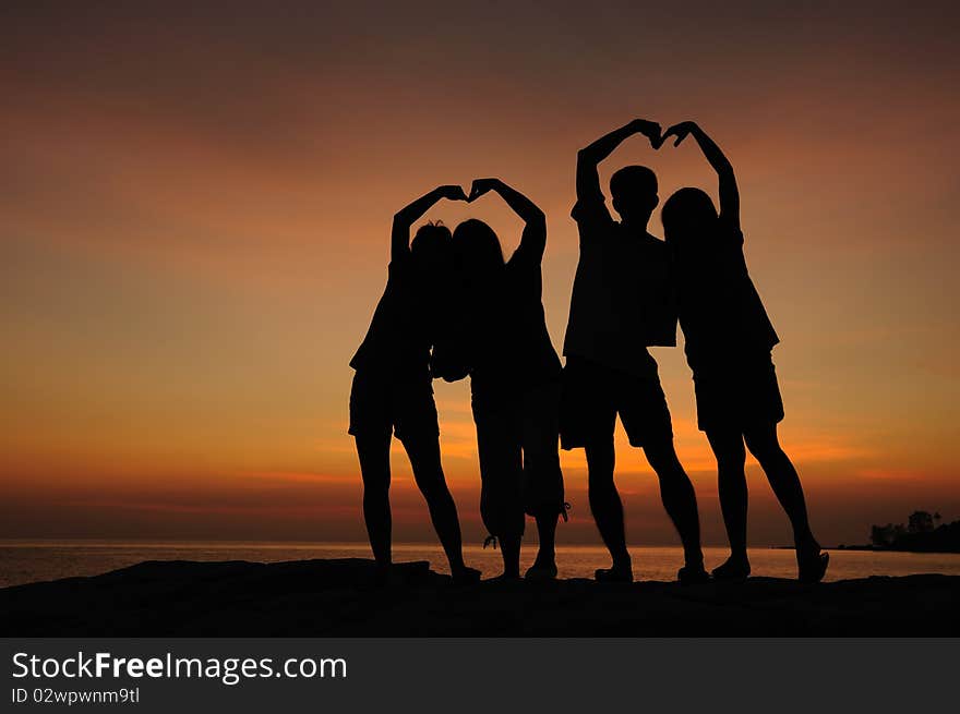 Silhouette of two couple of young people doing heart shape