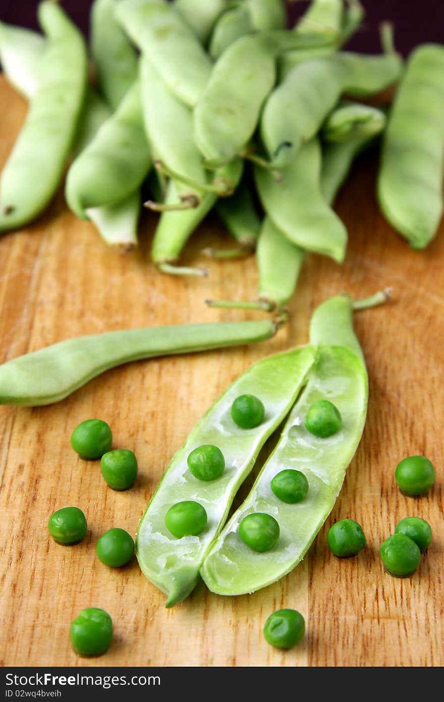 green peas in a wooden bowl and on the board