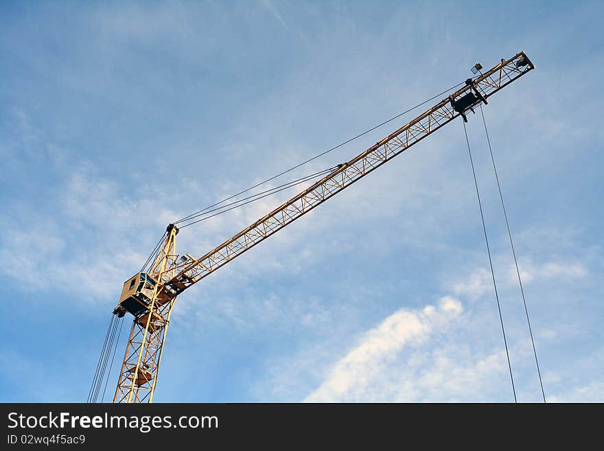 The building crane against the sky and clouds. The bottom view.