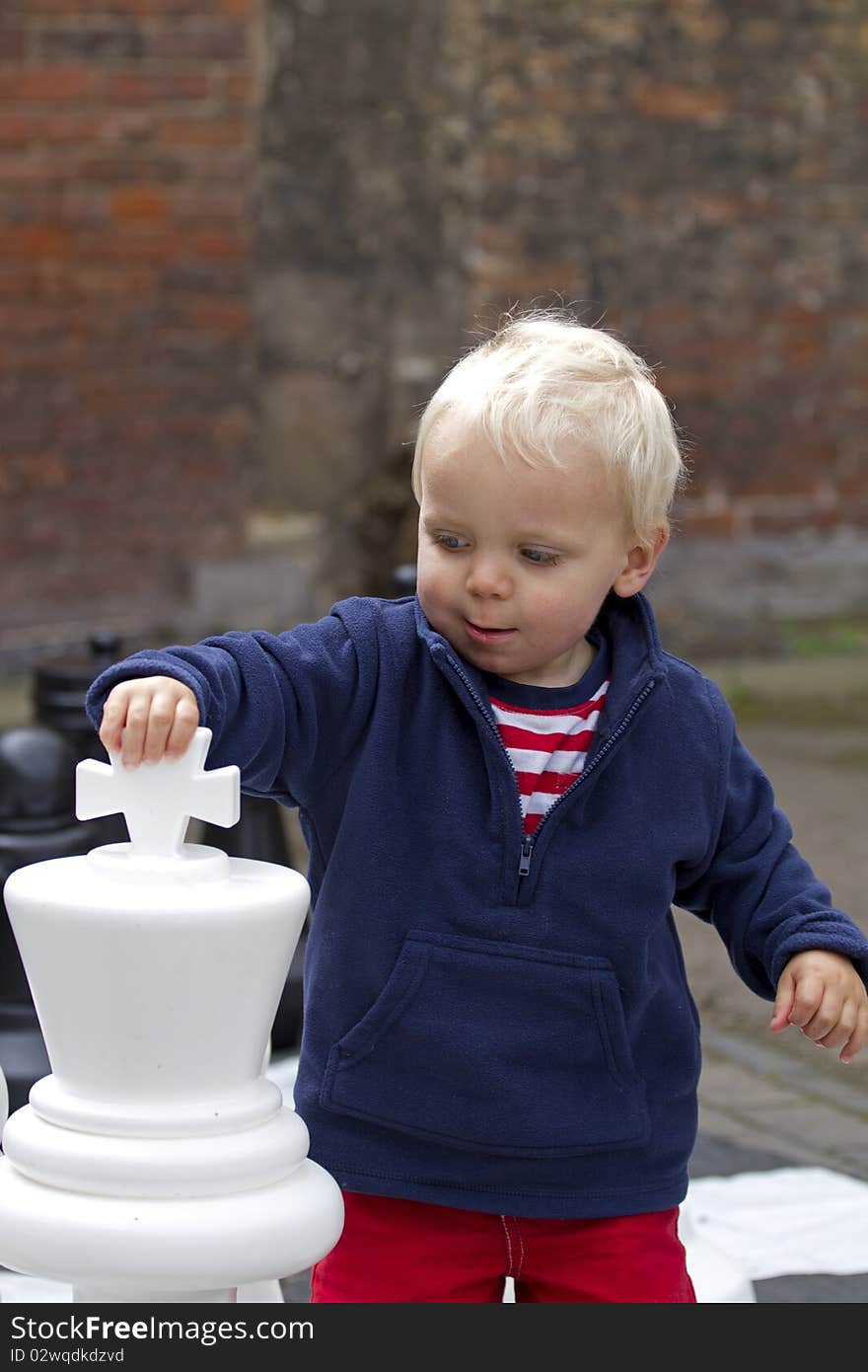 Cute blond toddler boy playing giant chess. Cute blond toddler boy playing giant chess