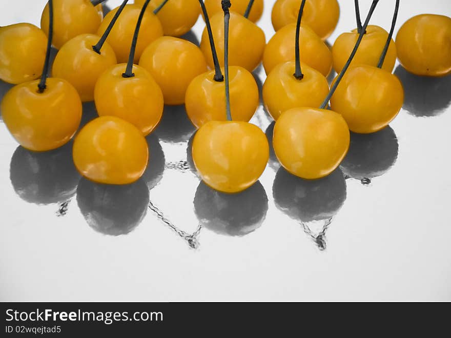 Yellow cherries with black and white reflection, selective coloring photo still life