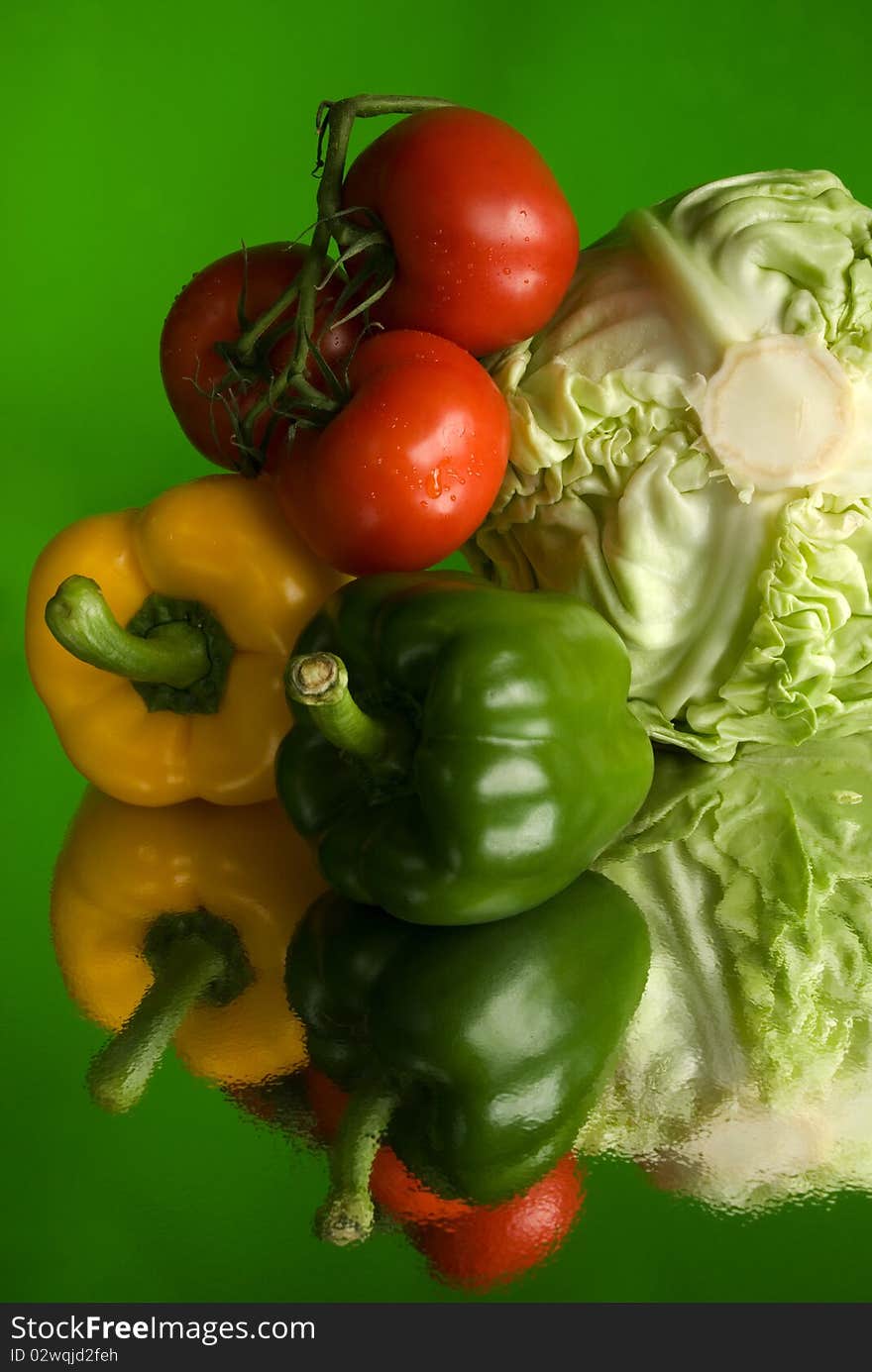 Cabbage, tomatoes and paprika with reflection against the green background< still life photography. Cabbage, tomatoes and paprika with reflection against the green background< still life photography