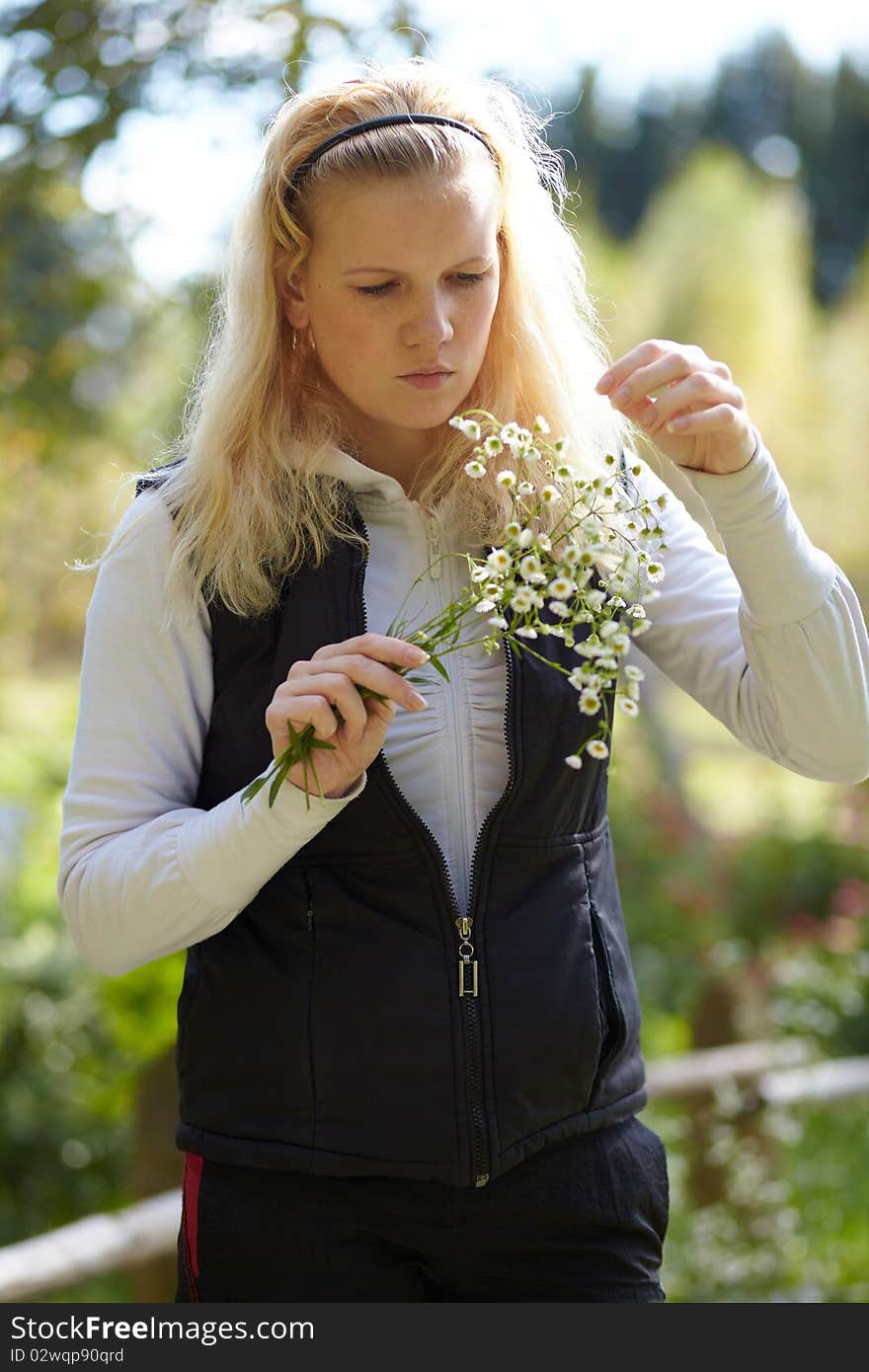 Blonde girl looks at the bouquet of daisies in autumn