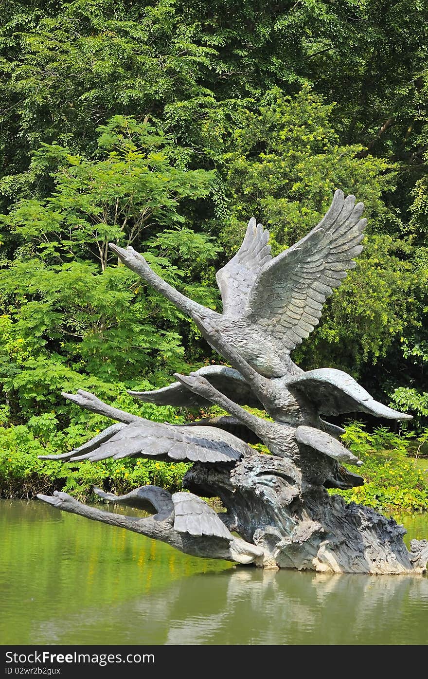 Metal swan sculptures in lake showing swans in states of flight.