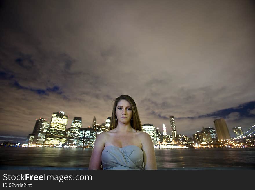 A young woman looks at you in front of a river and an urban skyline. A young woman looks at you in front of a river and an urban skyline