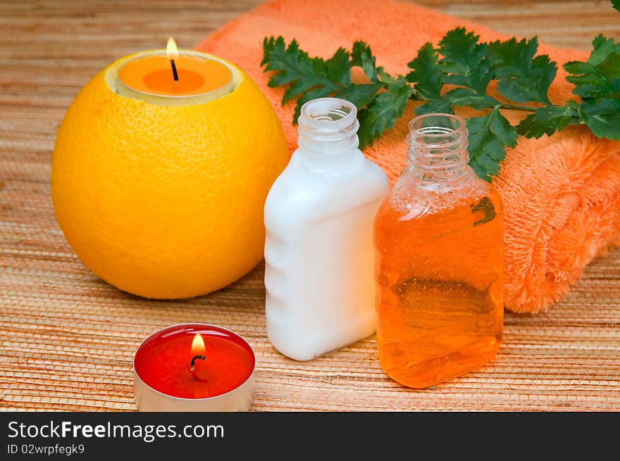 Orange towel, Fern branch and a burning candle in citrus. Orange towel, Fern branch and a burning candle in citrus