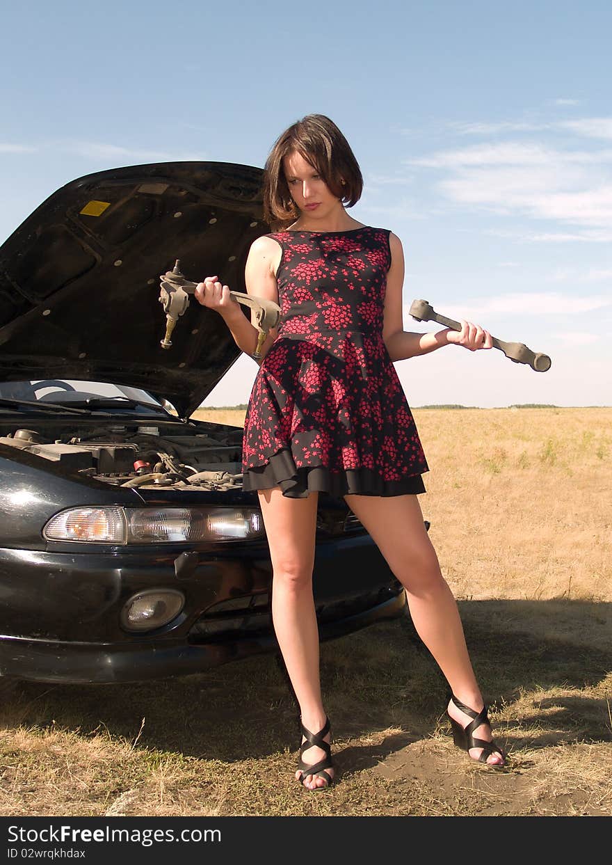 A beautiful young woman unsuccessfully trying to repair the car. A beautiful young woman unsuccessfully trying to repair the car