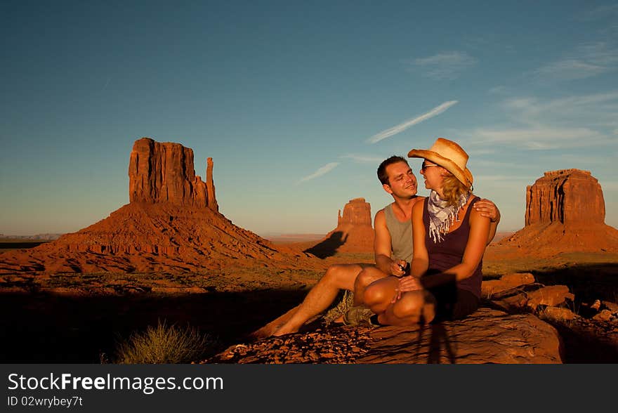 A portrait of a love couple posing in front of a rock found in monument valley utah. A portrait of a love couple posing in front of a rock found in monument valley utah