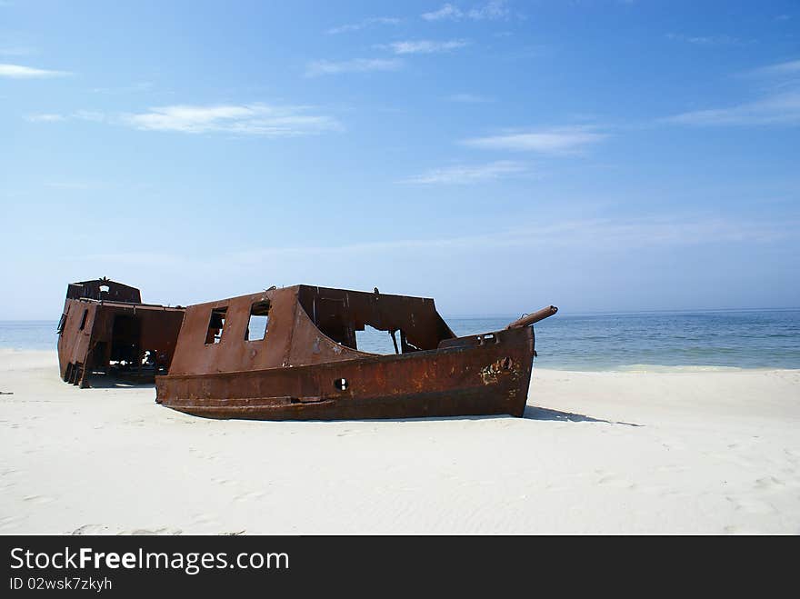 An old rusty ship thrown on a deserted beach. An old rusty ship thrown on a deserted beach