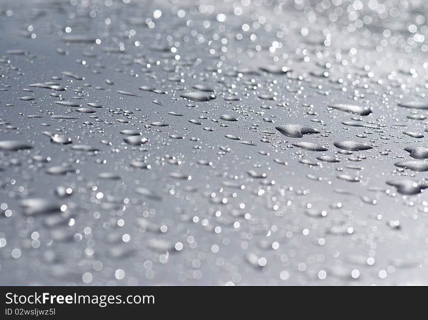 Raindrops on the hood of a gray car