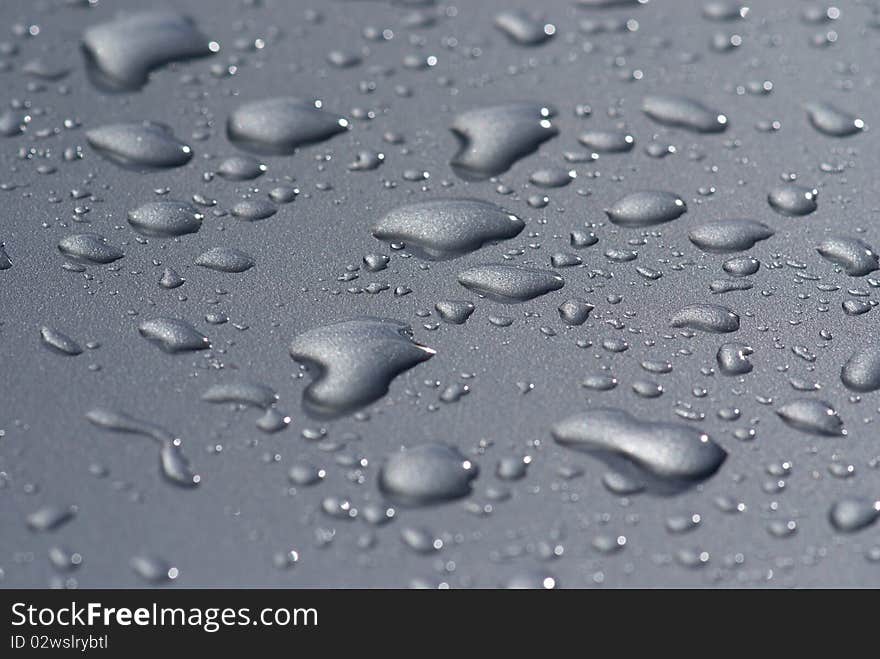 Raindrops on the hood of a gray car. Raindrops on the hood of a gray car