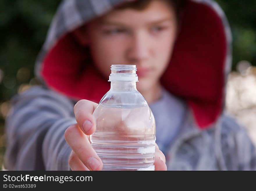 A young man holding out a bottle of cool, water.