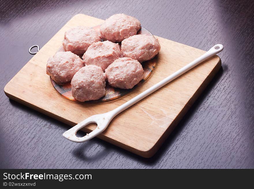 Raw hamburgers on cutting board with spatula