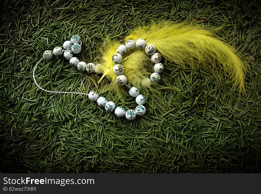 Beads and yellow feather against green needles