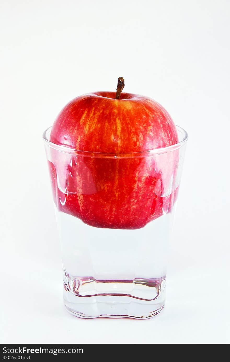 Apple in a glass of water isolated on white background