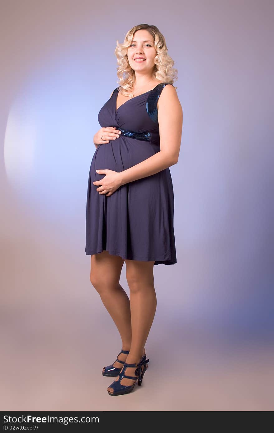 Photo of expectant mother in a dark blue dress in a studio