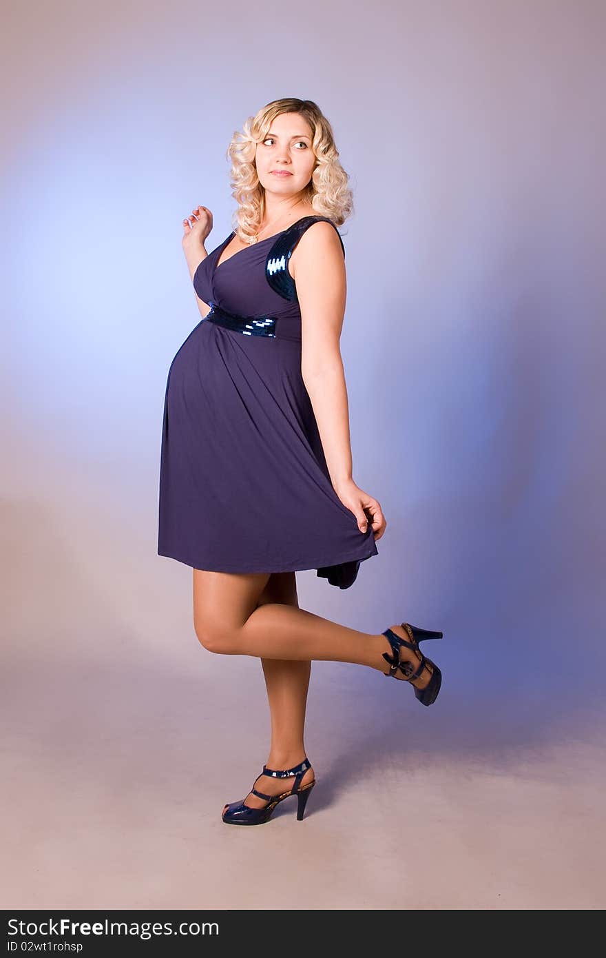 Photo of expectant mother in a dark blue dress in a studio