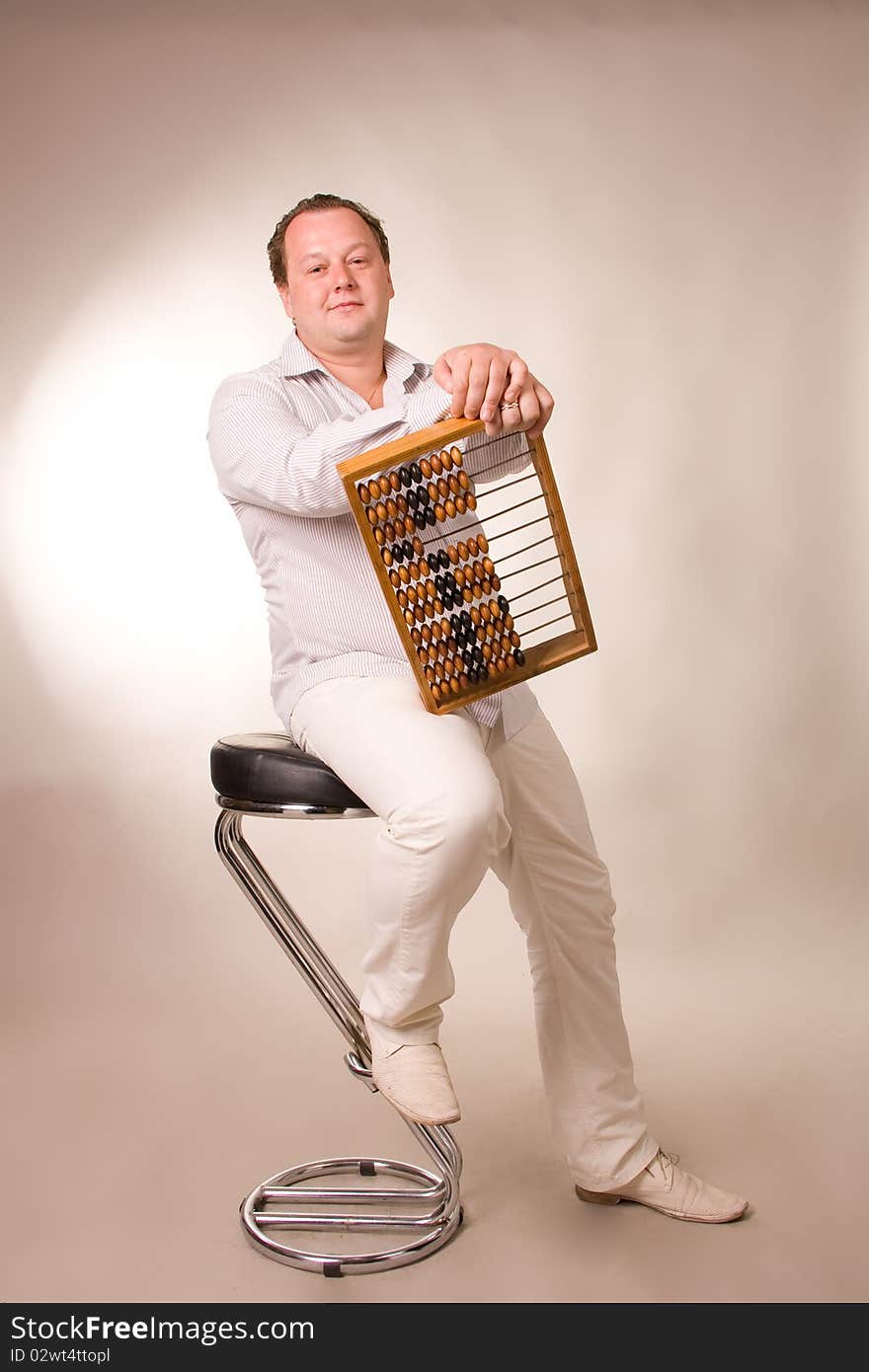 Man sits on a high chair with abacus in hands