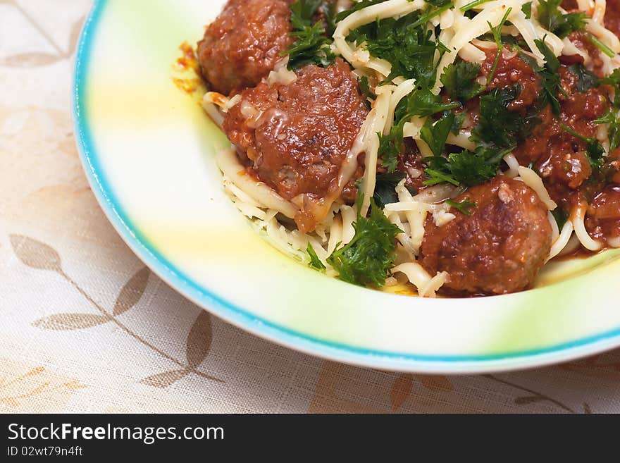 A dish with meatballs and spaghetti poured by sauce