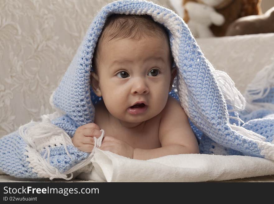 Horizontal image of a cute baby under a blue blanket