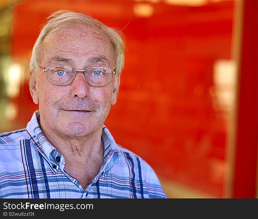 Portrait of a retired old man smiling against red background