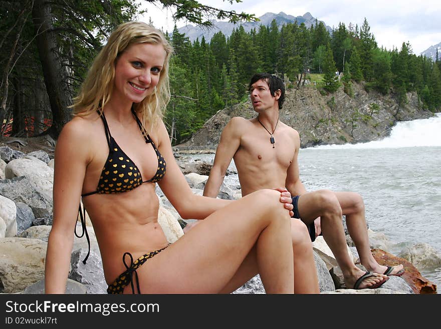 Couple sitting on rocks in swim suits. Couple sitting on rocks in swim suits