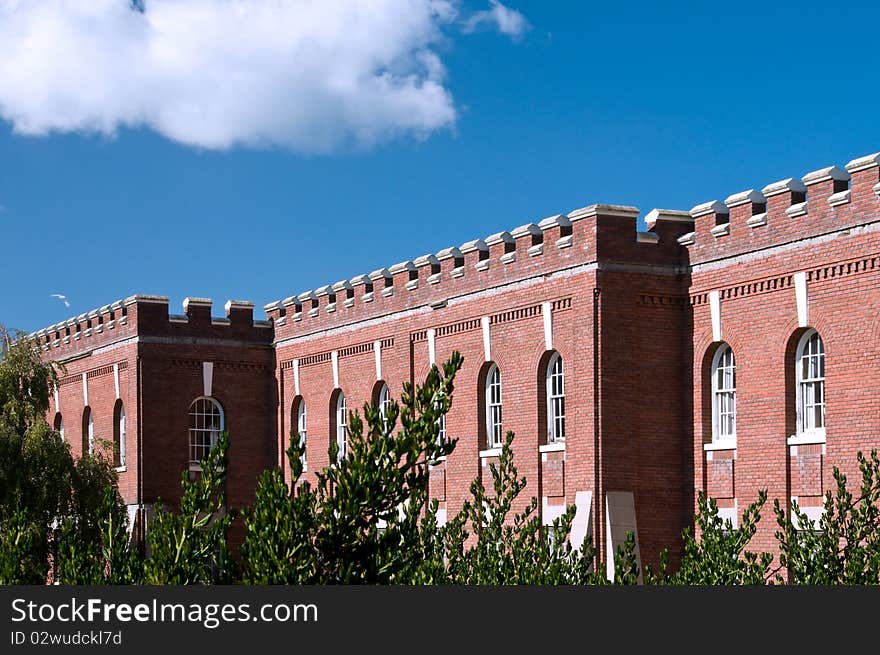 Red brick fort Victoria walls on blue sky background with green bushes in front. Red brick fort Victoria walls on blue sky background with green bushes in front