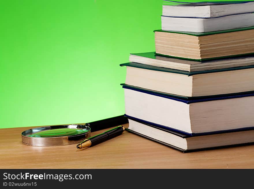 Book, pen and magnifying glass on table