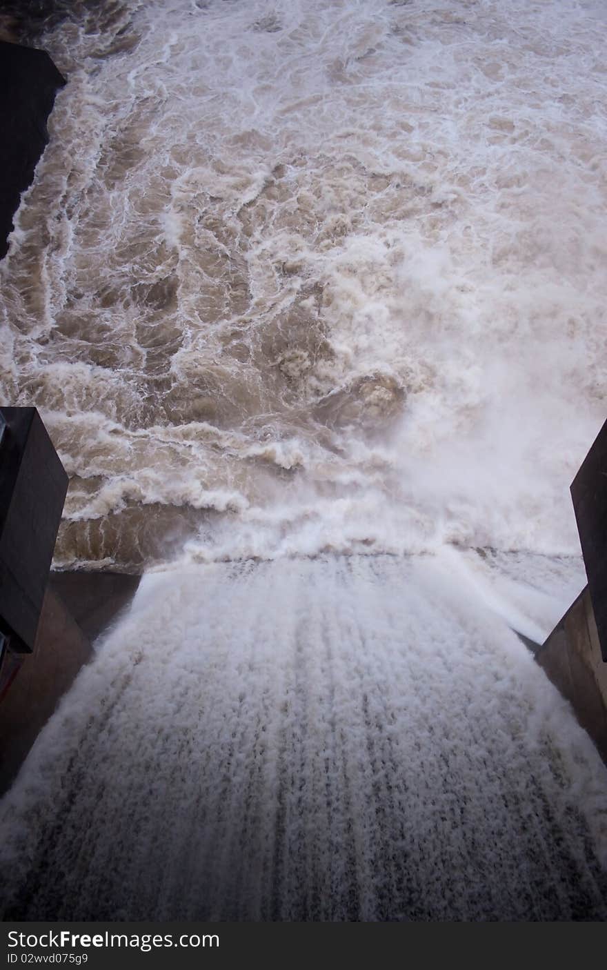 Looking down the spillway of a dam as water spills over. Focus on the water below. Looking down the spillway of a dam as water spills over. Focus on the water below.