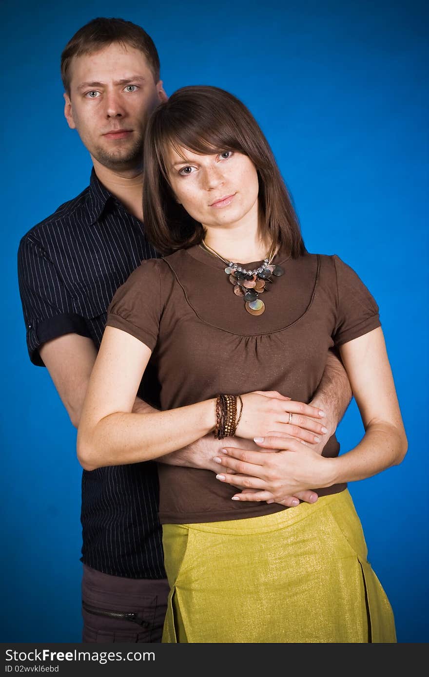 Portrait of a happy young couple hugging each other against blue background