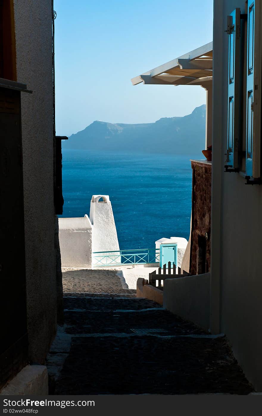 View on the sea through a small street on top of the caldera in Santorini, Greece. View on the sea through a small street on top of the caldera in Santorini, Greece.