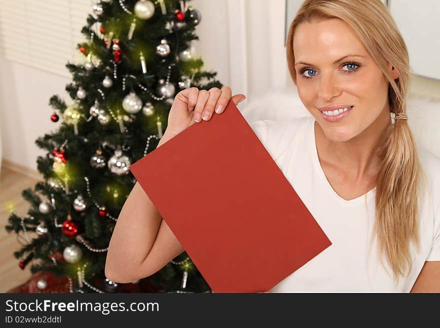 Beautiful blond female angel holding a plate in front of a christmas-tree. Beautiful blond female angel holding a plate in front of a christmas-tree