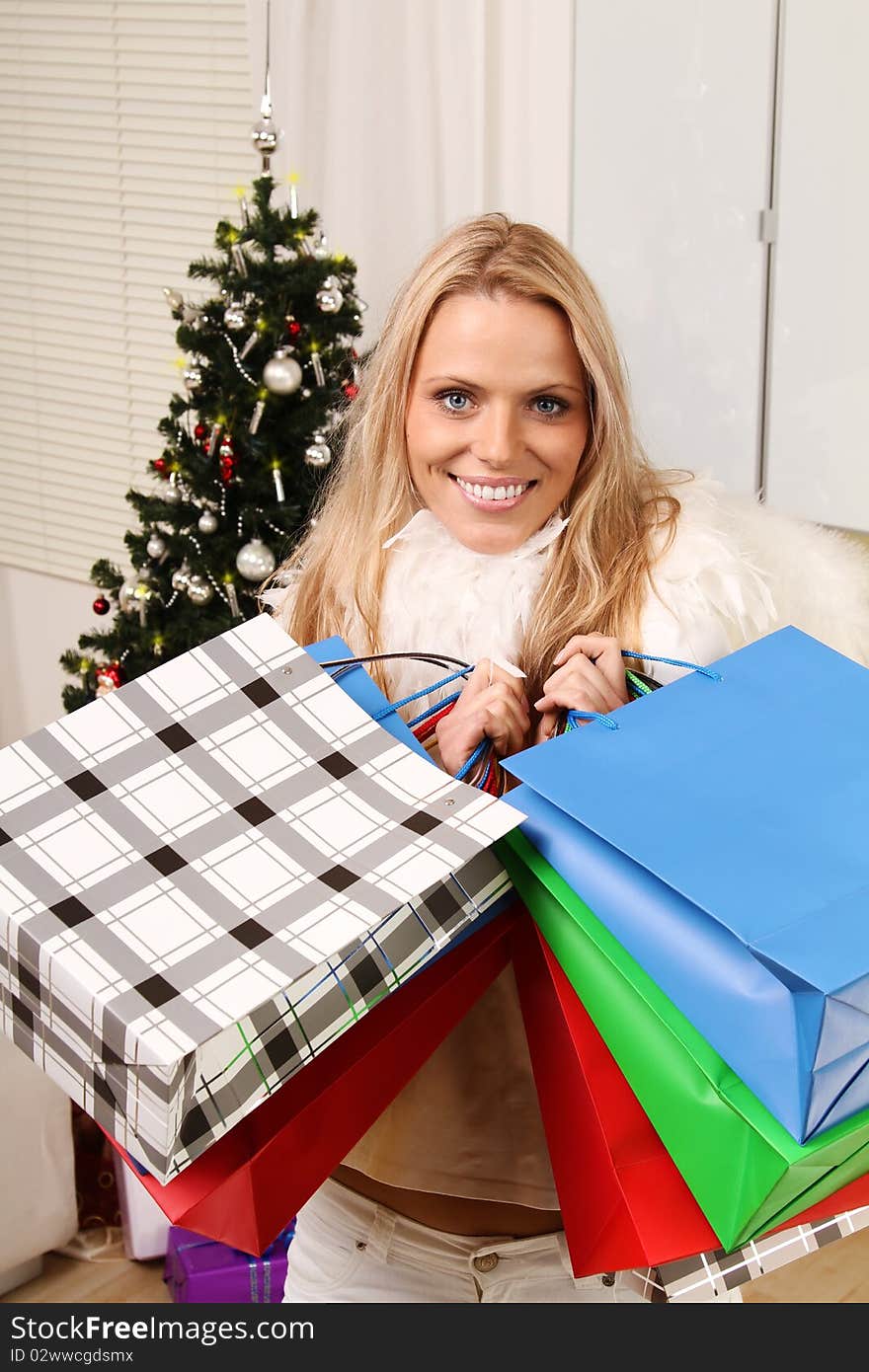 Beautiful blond female angel holding some shopping bags in front of a christmas-tree. Beautiful blond female angel holding some shopping bags in front of a christmas-tree