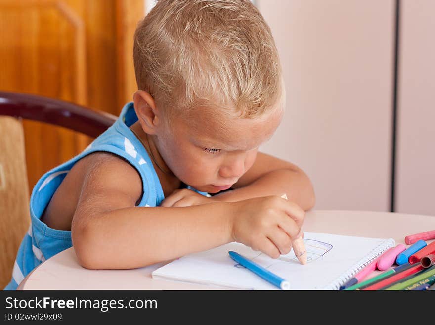 Little boy crayons at desk