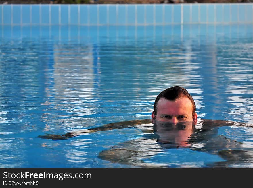 Man swimming in swimming pool. Summer time.