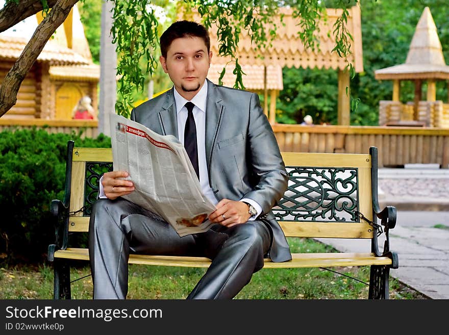 Young businessman reading a newspaper in the park